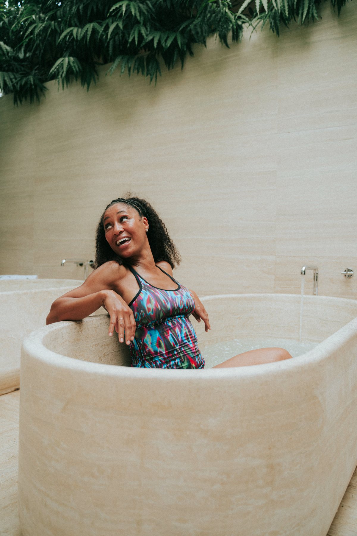 A guest laughing as she settles into a stone ice bath at Garden Club