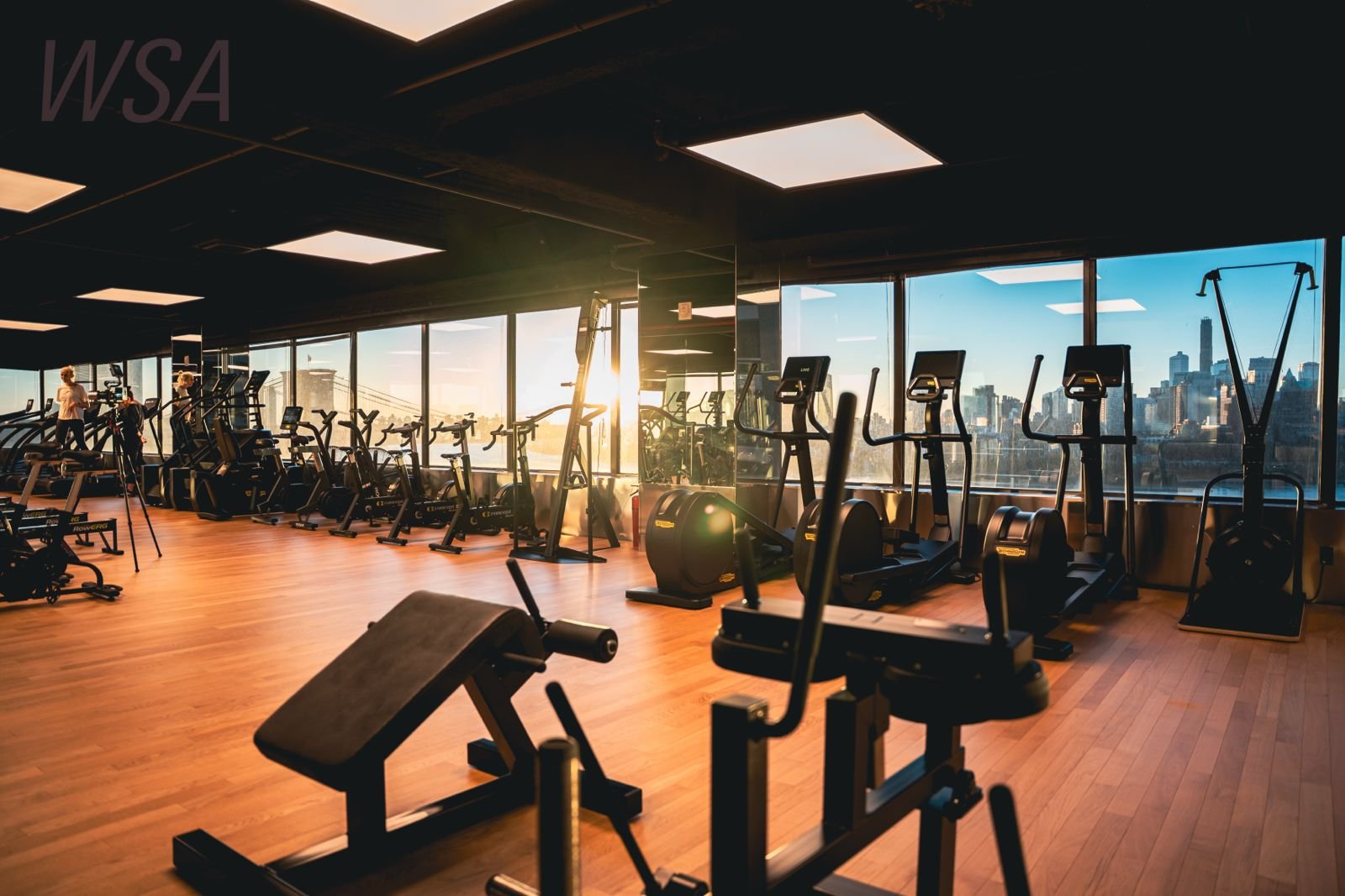 The cardio floor at sunset, with Lower Manhattan and the Brooklyn Bridge through the windows
