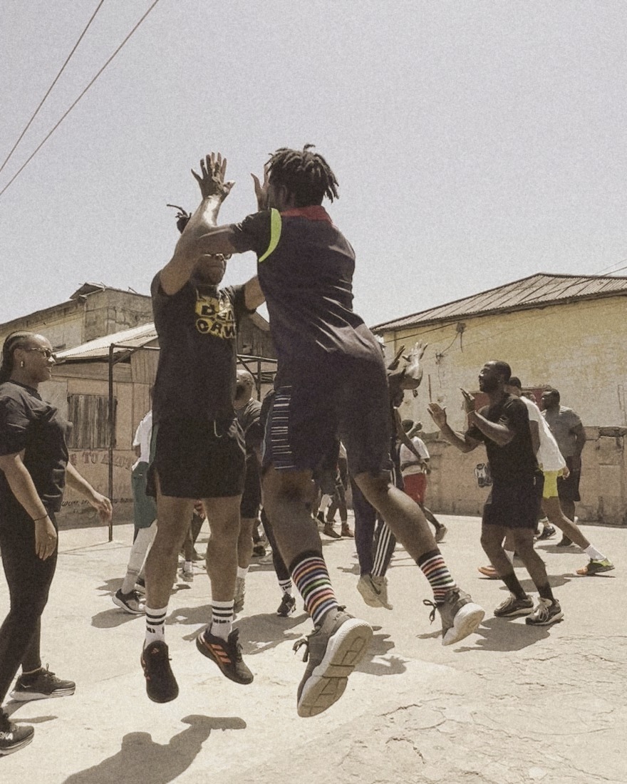 Guests and local fighters mid-air in a partner drill on the rooftop gym, Accra