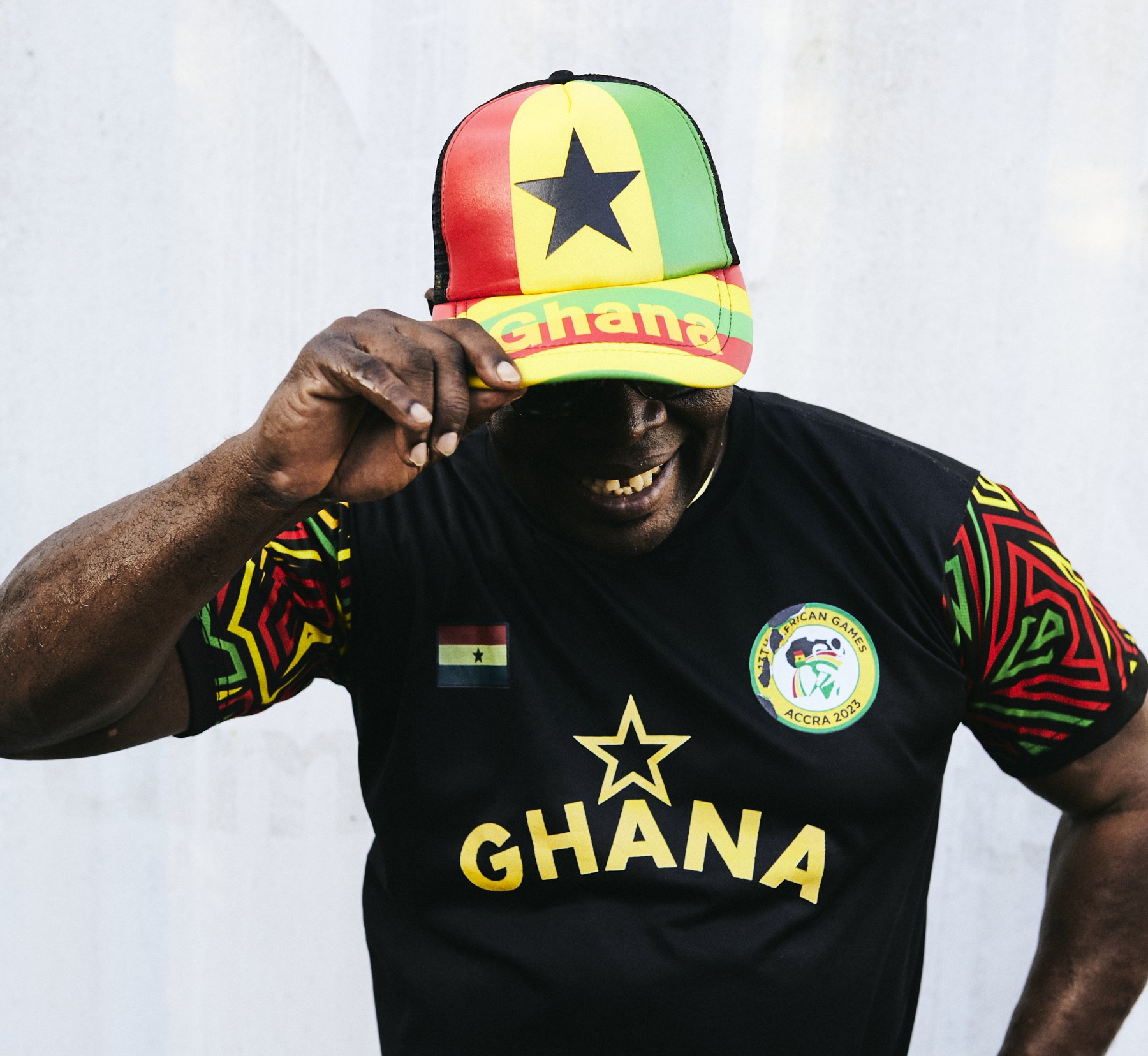 Coach Ofori Asare in a Ghana cap and national team shirt, laughing